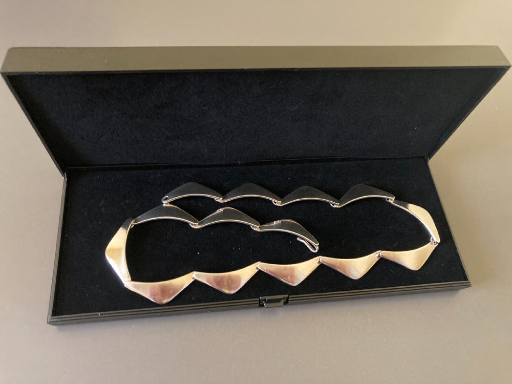 A vintage Danish silver link necklace featuring geometric, articulated segments arranged in a circular design. View V