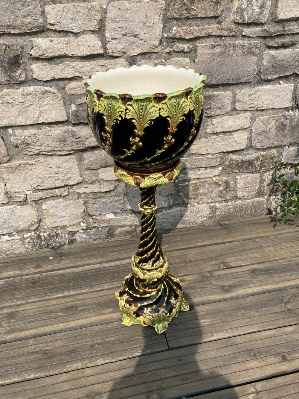 An Art Nouveau majolica ceramic jardiniere resting on a tall twisted pedestal stand decorated with dark brown glaze and raised green acanthus leaf relief motifs. View II