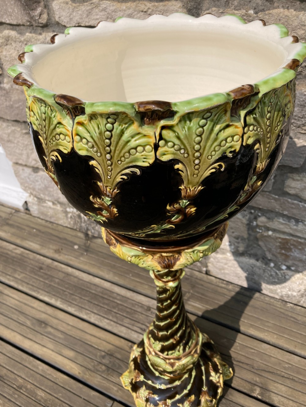 An Art Nouveau majolica ceramic jardiniere resting on a tall twisted pedestal stand decorated with dark brown glaze and raised green acanthus leaf relief motifs. View III
