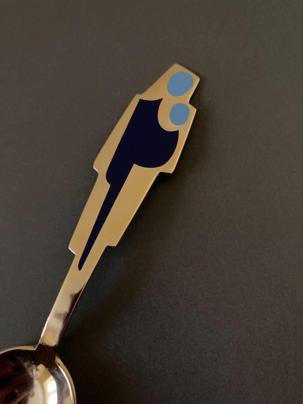 A gold gilt sterling silver spoon featuring a stylized blue enamel abstract design on the handle, dating from 1962. View II