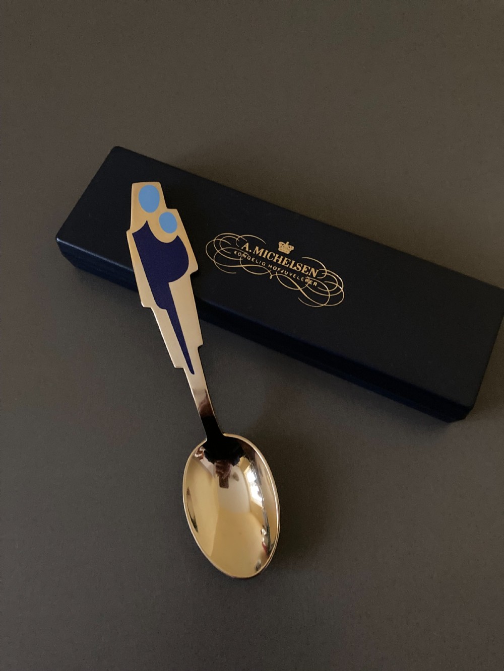 A gold gilt sterling silver spoon featuring a stylized blue enamel abstract design on the handle, dating from 1962. View III