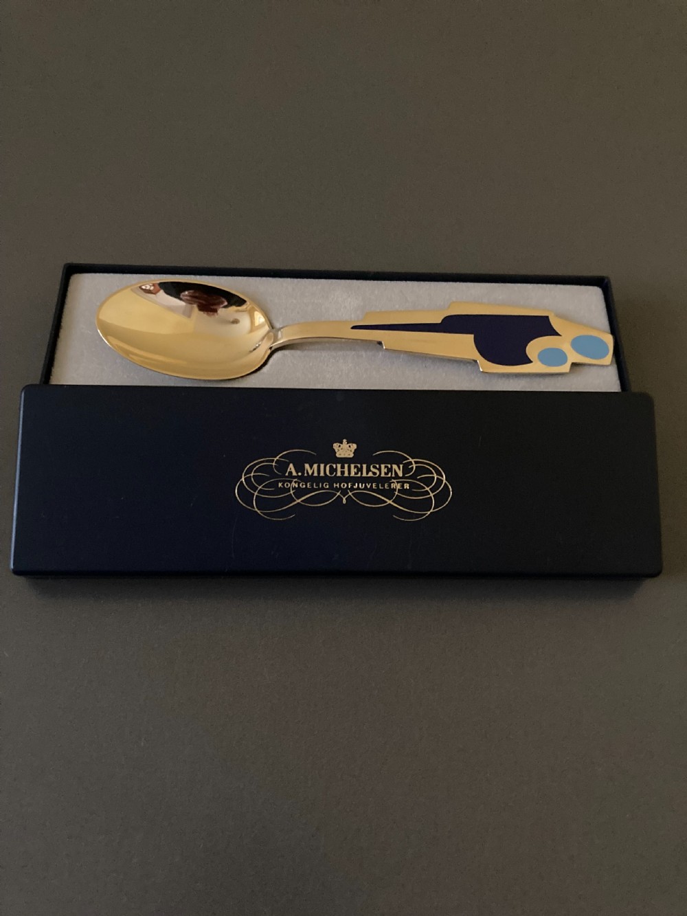 A gold gilt sterling silver spoon featuring a stylized blue enamel abstract design on the handle, dating from 1962. View VI
