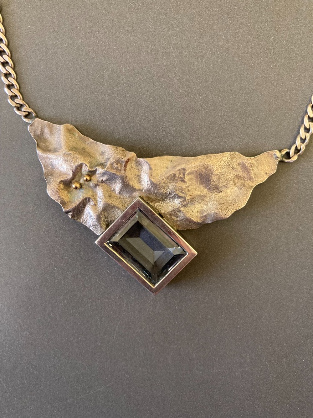 A 1960s sterling silver curb chain necklace featuring a textured asymmetrical pendant with an emerald-cut blue topaz stone. View III