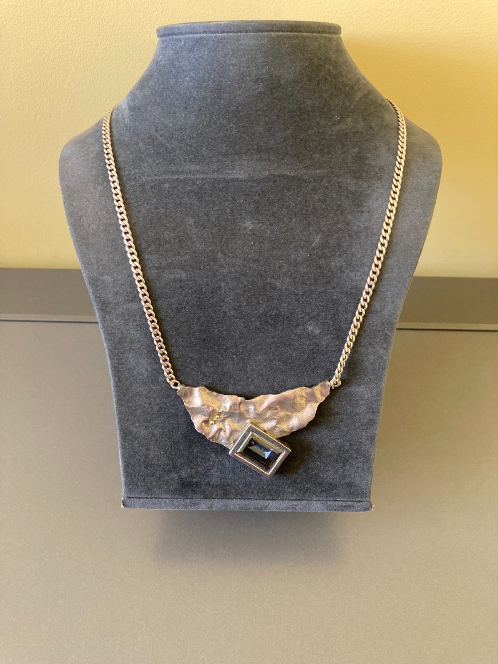 A 1960s sterling silver curb chain necklace featuring a textured asymmetrical pendant with an emerald-cut blue topaz stone. View IV