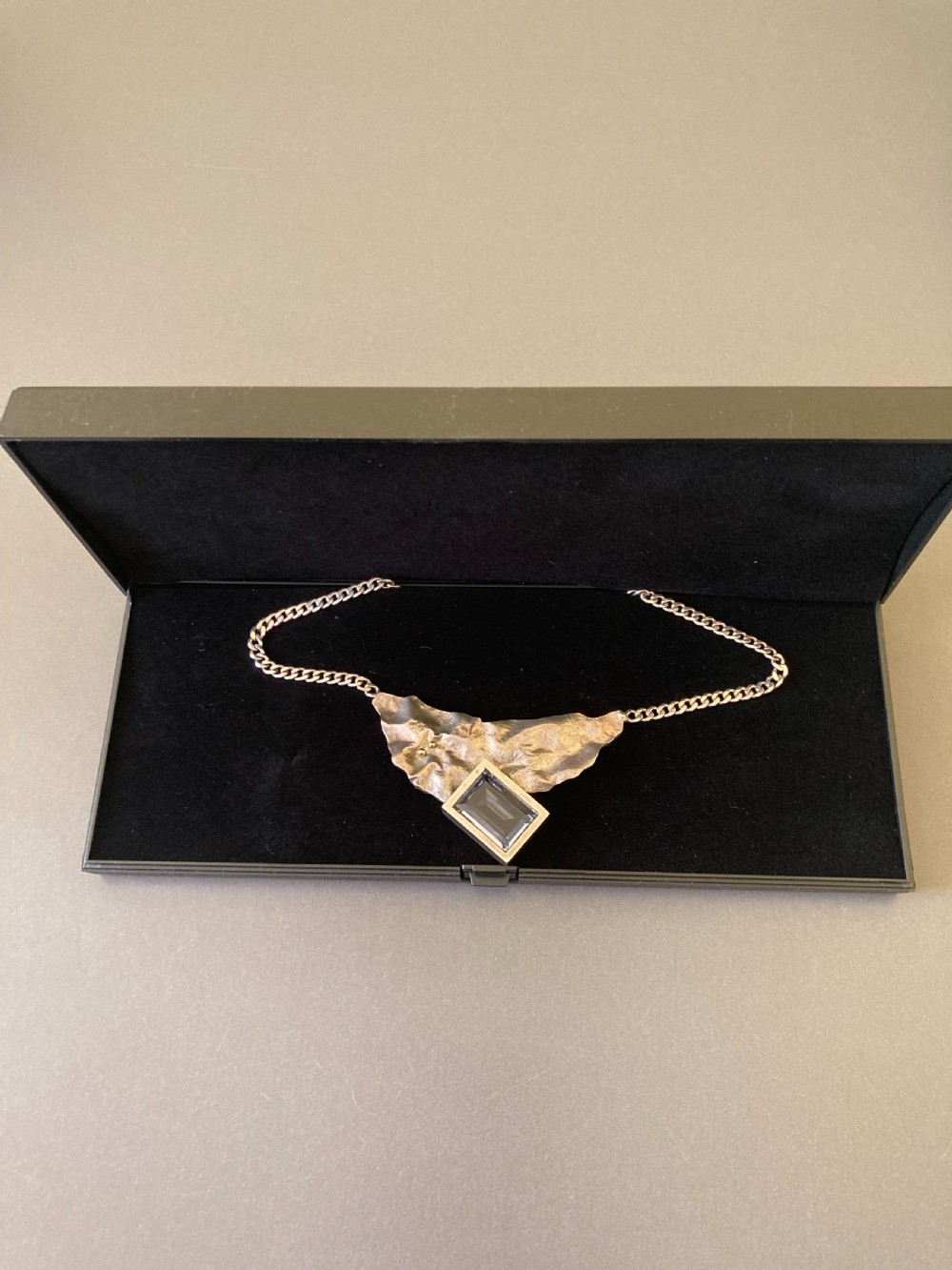 A 1960s sterling silver curb chain necklace featuring a textured asymmetrical pendant with an emerald-cut blue topaz stone. View VII