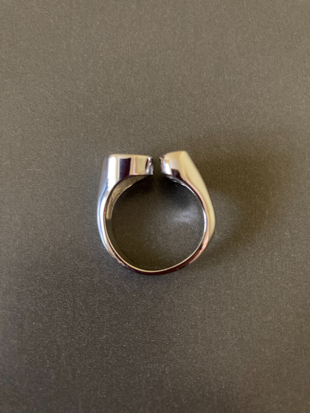 A Danish sterling silver ring from the 1960s featuring an asymmetrical modernist design with an open circle motif, a polished solid disc, and a bezel-set round zirconia stone. View IV