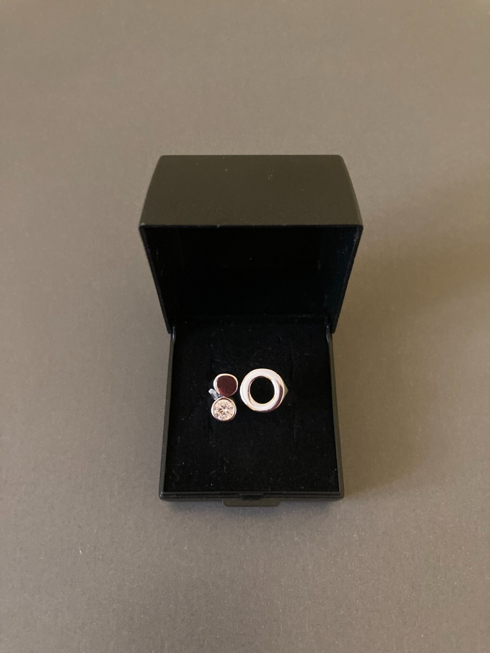 A Danish sterling silver ring from the 1960s featuring an asymmetrical modernist design with an open circle motif, a polished solid disc, and a bezel-set round zirconia stone. View V