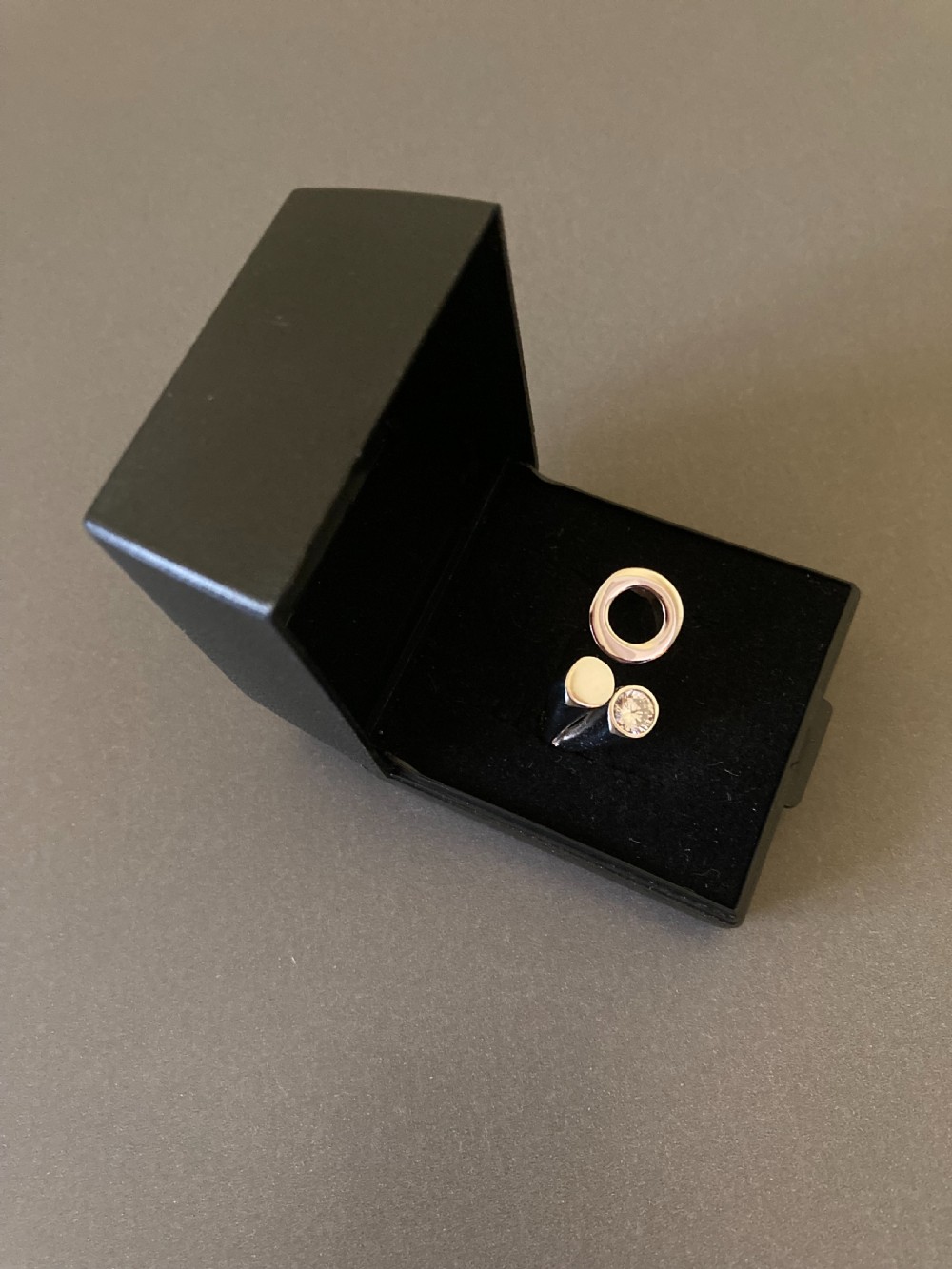 A Danish sterling silver ring from the 1960s featuring an asymmetrical modernist design with an open circle motif, a polished solid disc, and a bezel-set round zirconia stone. View VI