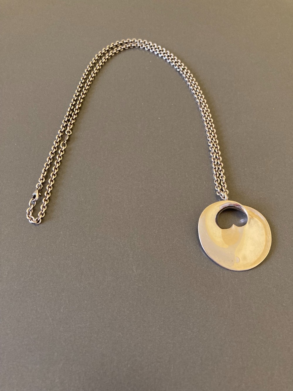 A sterling silver circular pendant featuring an organic cutout design attached to a double fine silver chain. View II