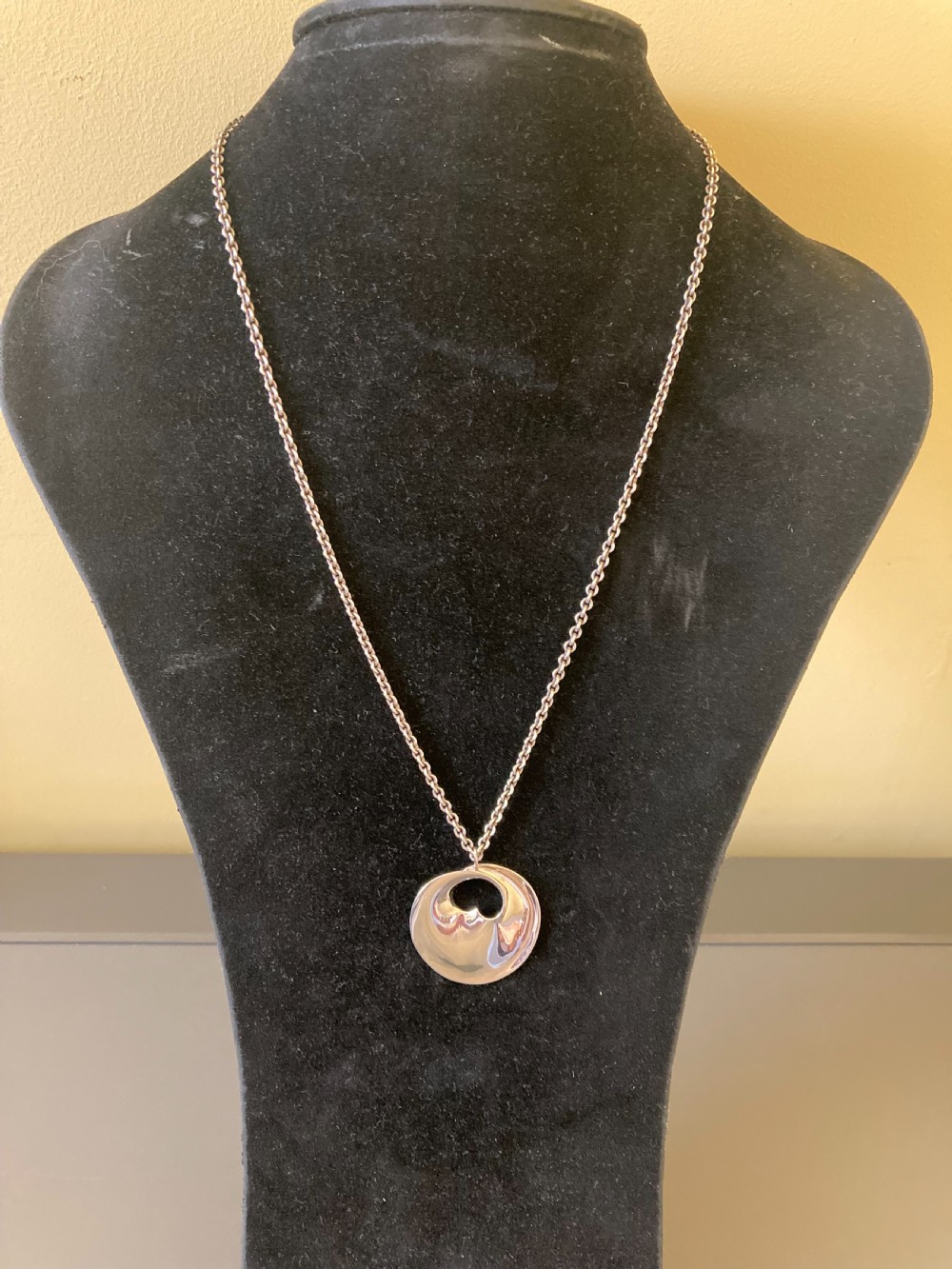A sterling silver circular pendant featuring an organic cutout design attached to a double fine silver chain. View III