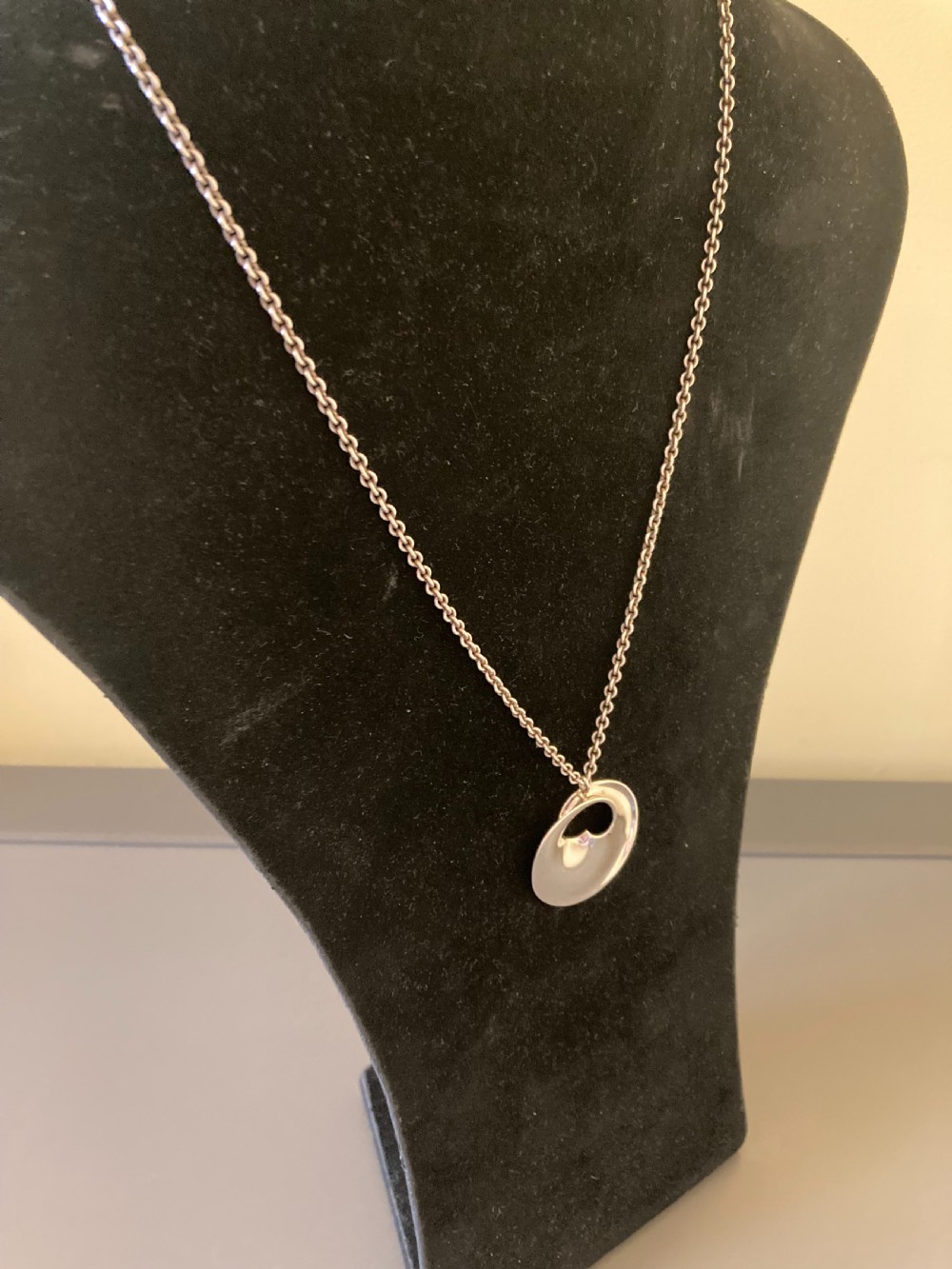 A sterling silver circular pendant featuring an organic cutout design attached to a double fine silver chain. View IV
