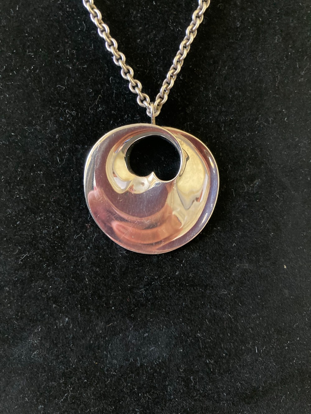A sterling silver circular pendant featuring an organic cutout design attached to a double fine silver chain. View V