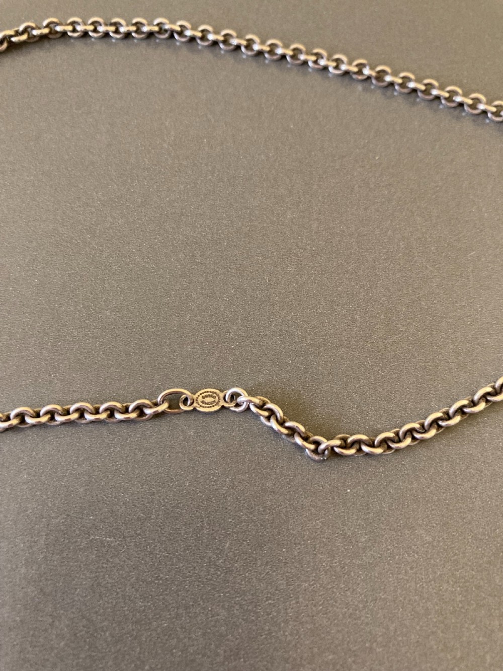 A sterling silver circular pendant featuring an organic cutout design attached to a double fine silver chain. View VI