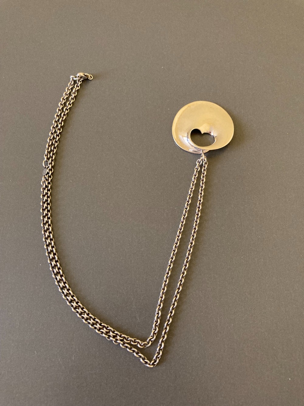 A sterling silver circular pendant featuring an organic cutout design attached to a double fine silver chain. View VII
