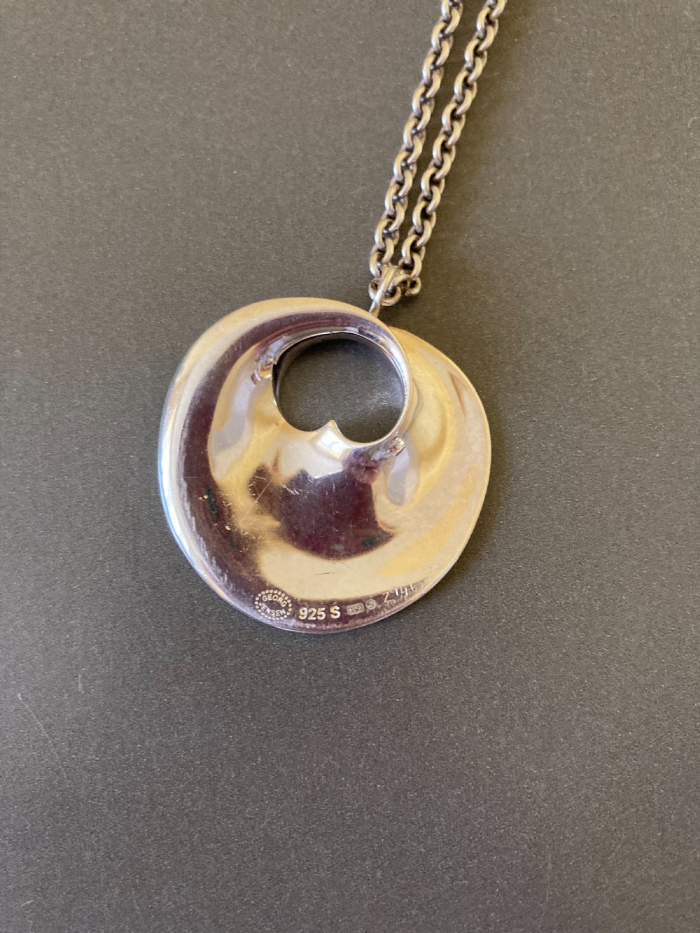 A sterling silver circular pendant featuring an organic cutout design attached to a double fine silver chain. View IX