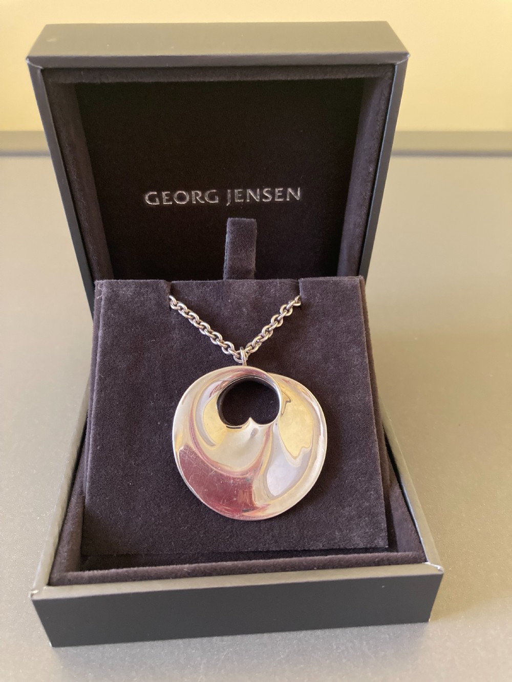 A sterling silver circular pendant featuring an organic cutout design attached to a double fine silver chain. View X