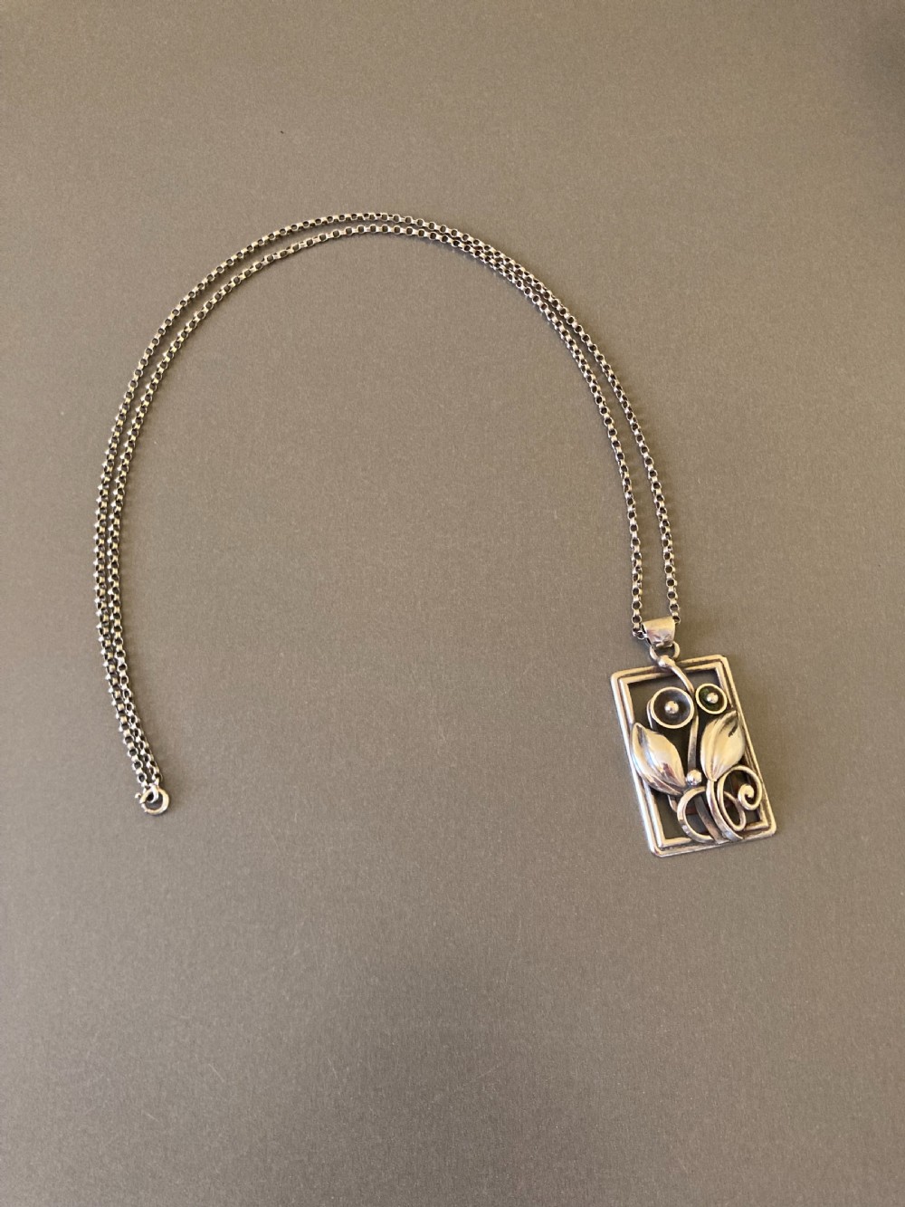 A rectangular sterling silver pendant featuring openwork foliage motifs on a thin silver link chain. View II