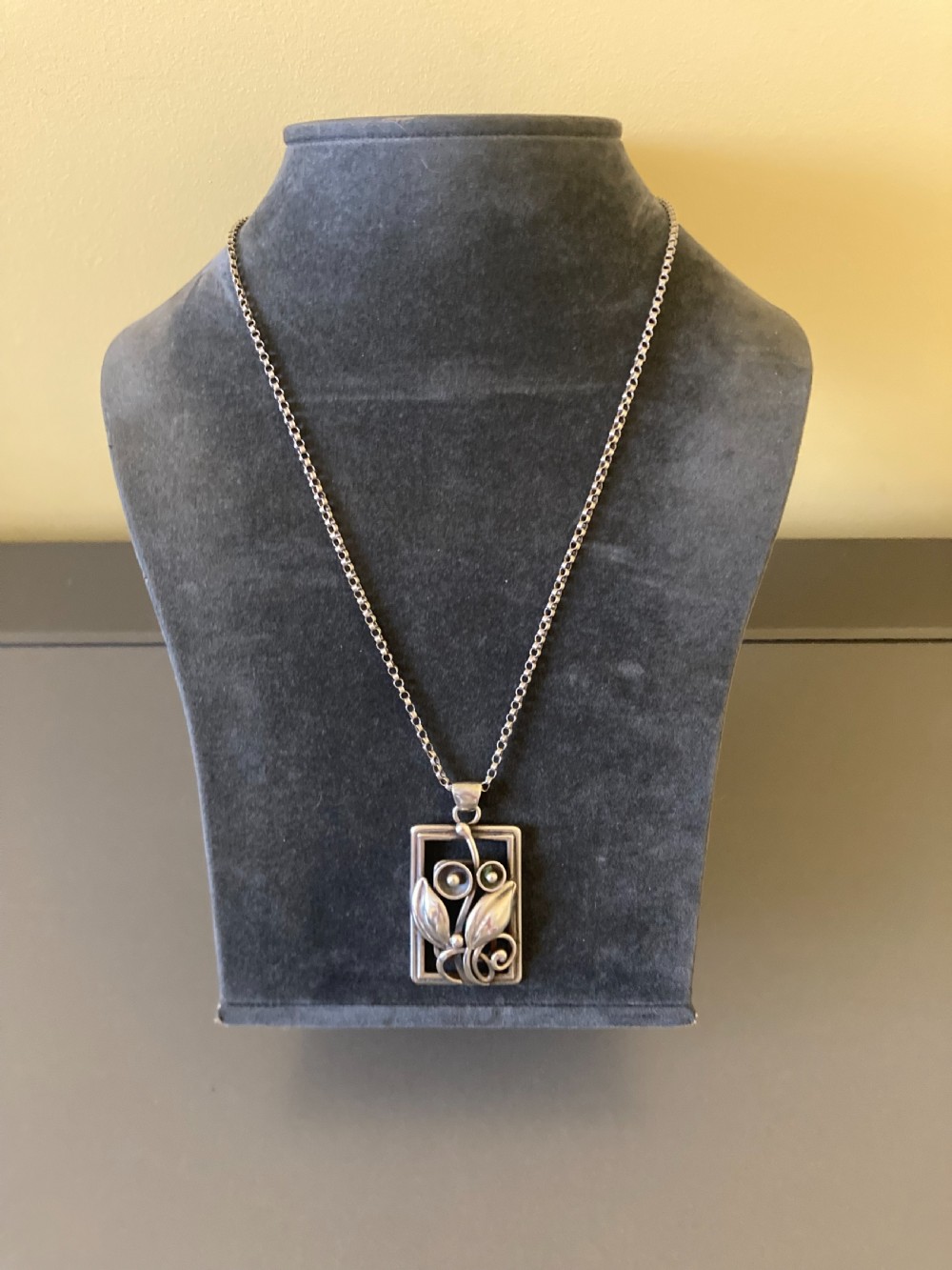 A rectangular sterling silver pendant featuring openwork foliage motifs on a thin silver link chain. View III