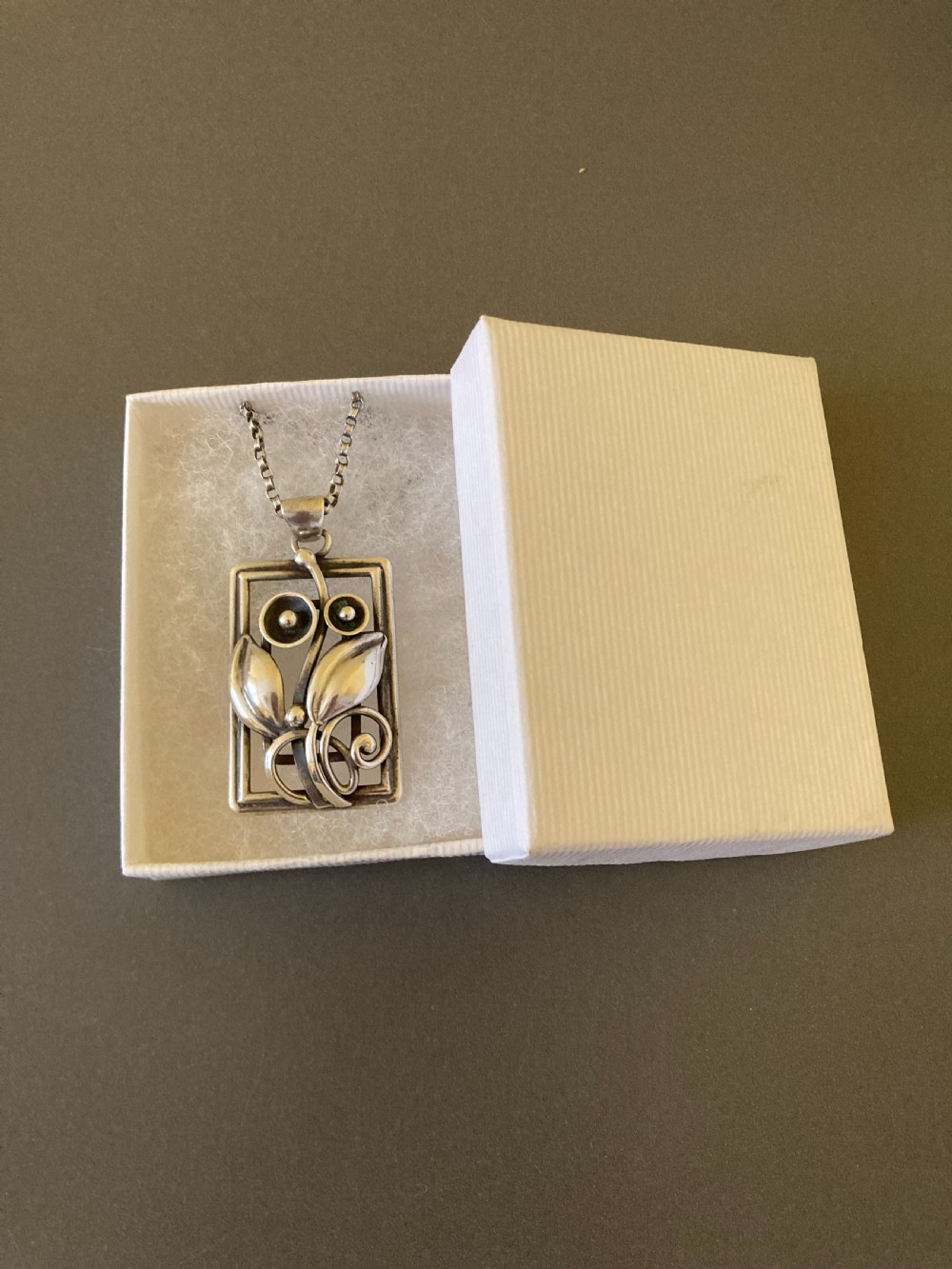 A rectangular sterling silver pendant featuring openwork foliage motifs on a thin silver link chain. View VI