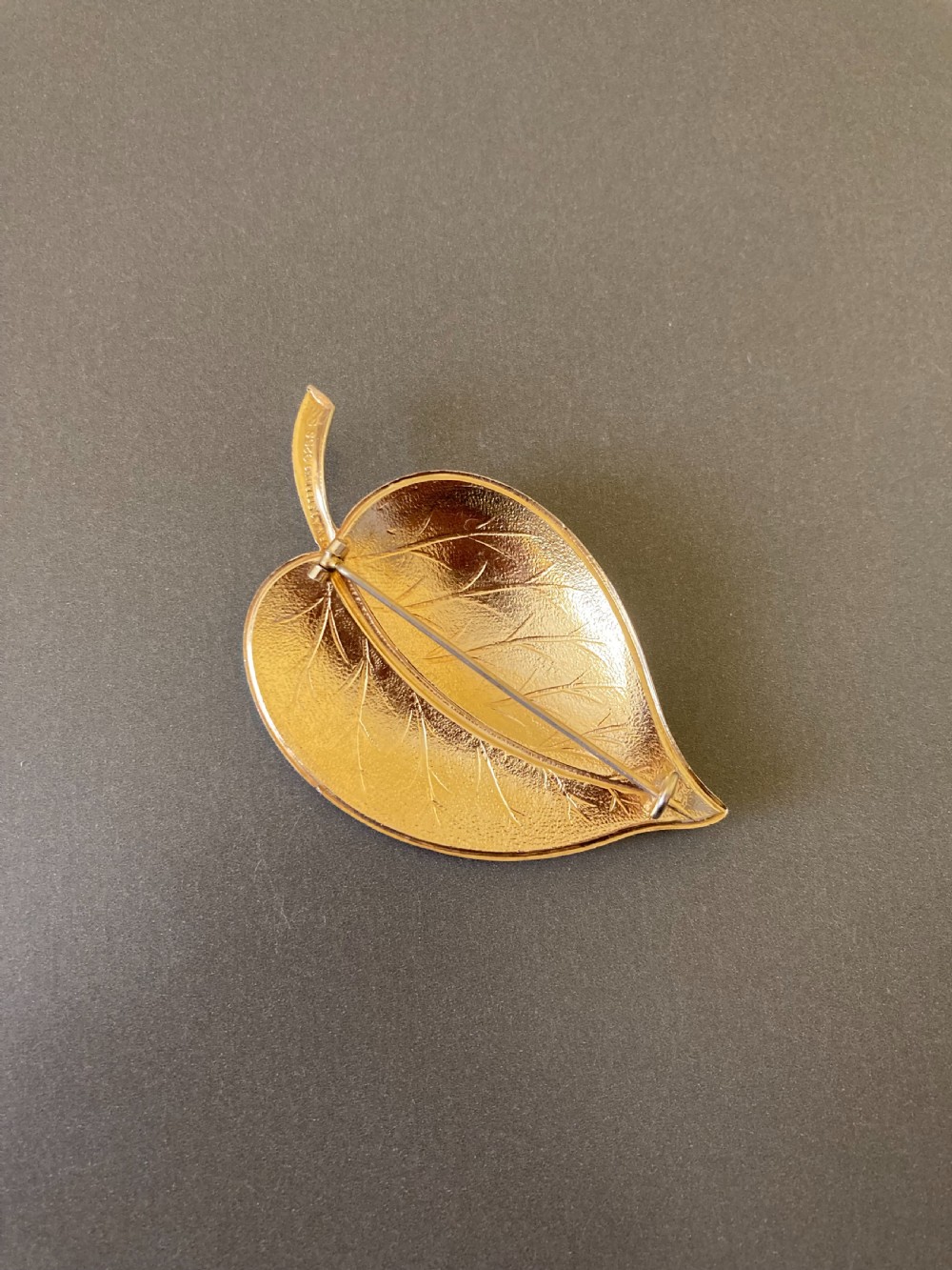 A leaf-shaped white guilloche enamel brooch with silver gilt edges and a curved stem. View III