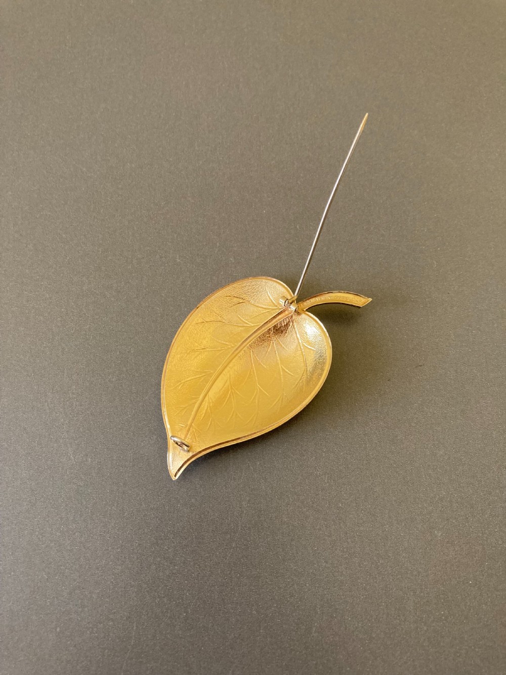A leaf-shaped white guilloche enamel brooch with silver gilt edges and a curved stem. View IV