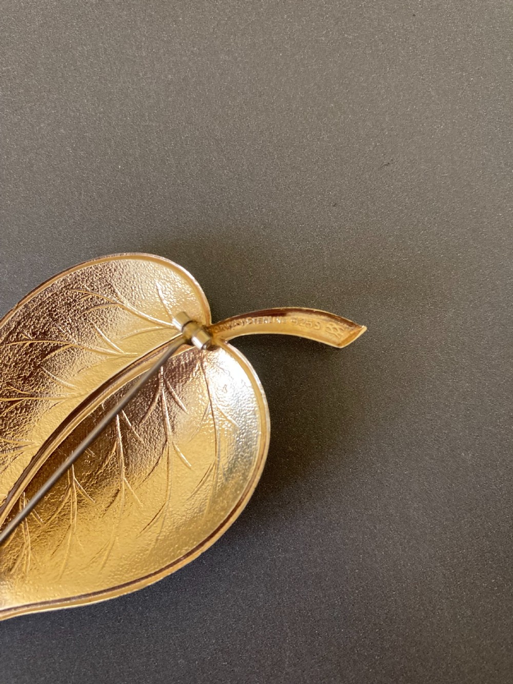 A leaf-shaped white guilloche enamel brooch with silver gilt edges and a curved stem. View V