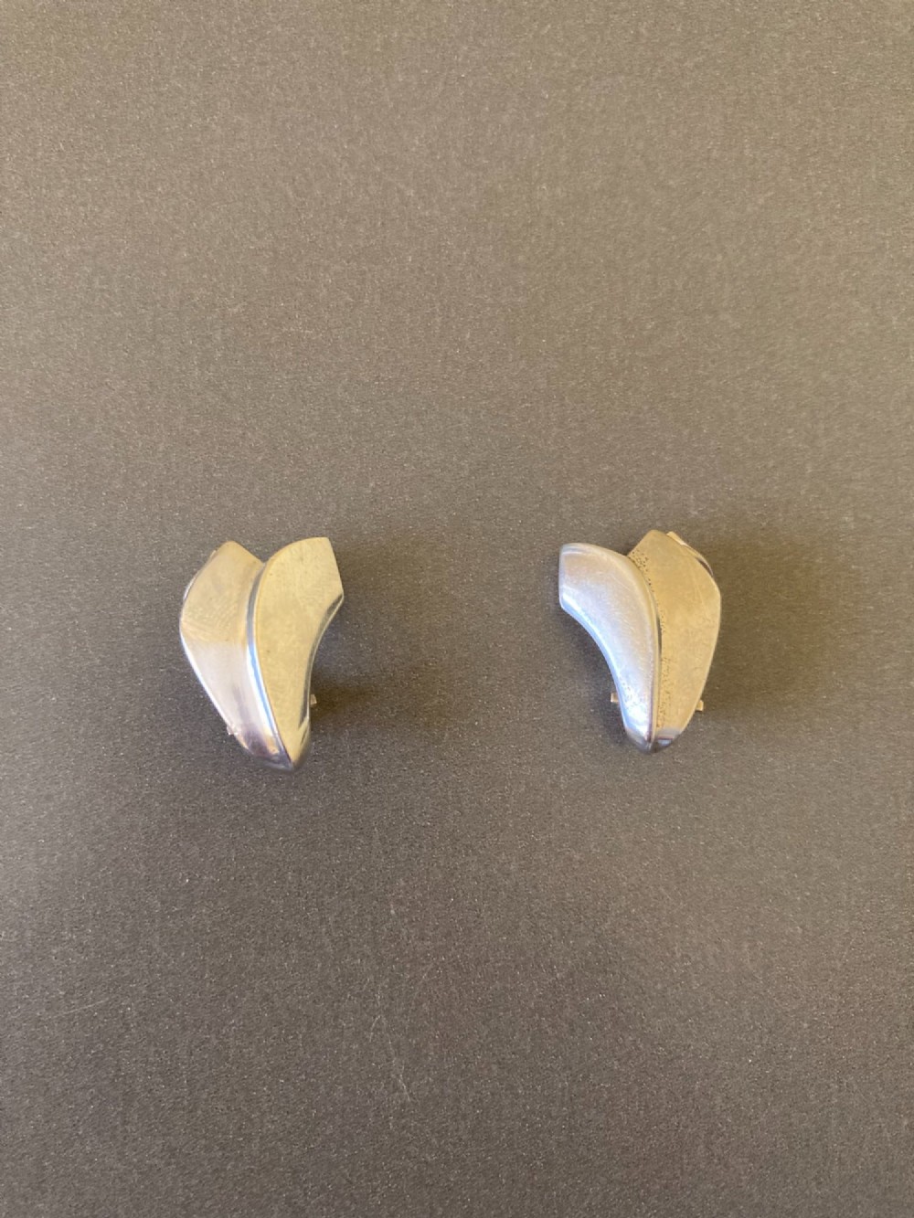 A pair of Georg Jensen Danish sterling silver lotus leaf clip-on earrings displayed on a dark grey velvet pouch. View II