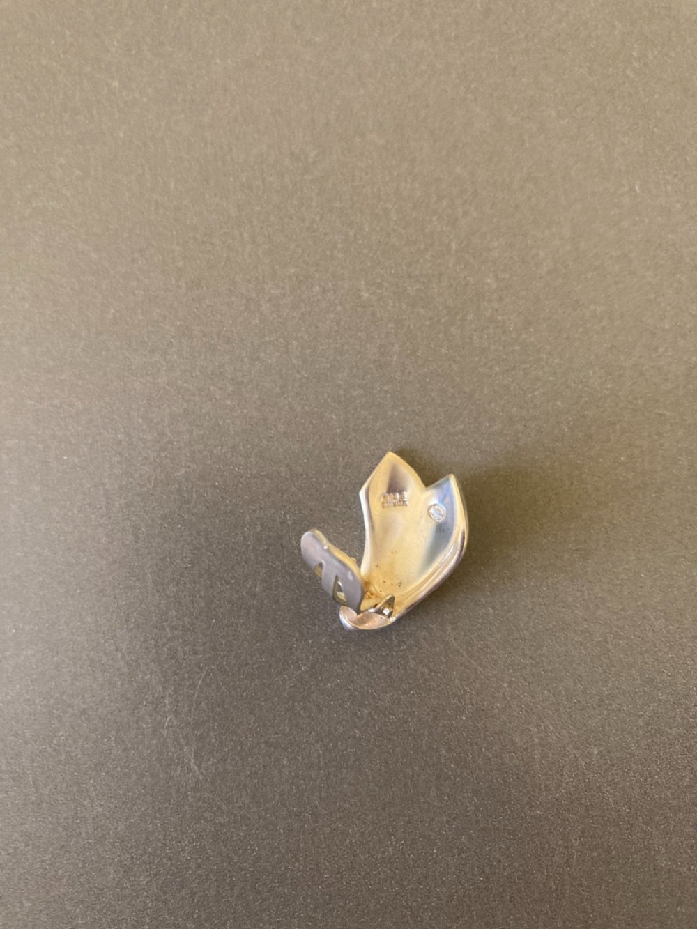 A pair of Georg Jensen Danish sterling silver lotus leaf clip-on earrings displayed on a dark grey velvet pouch. View IV
