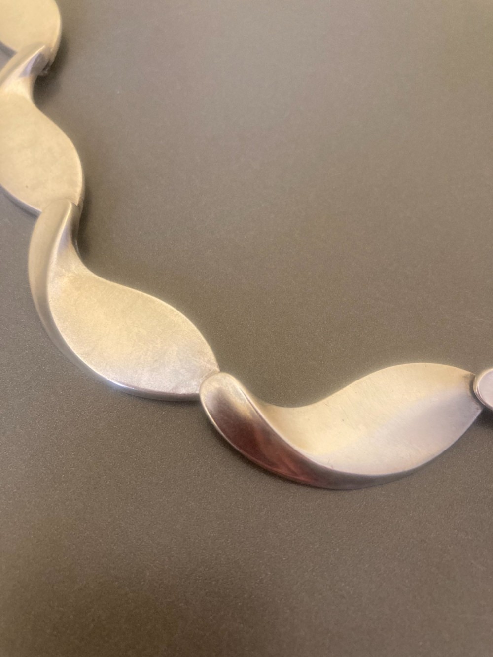A Georg Jensen 1960s Danish sterling silver necklace featuring contoured, wave-like articulated links arranged in a circular shape. View II