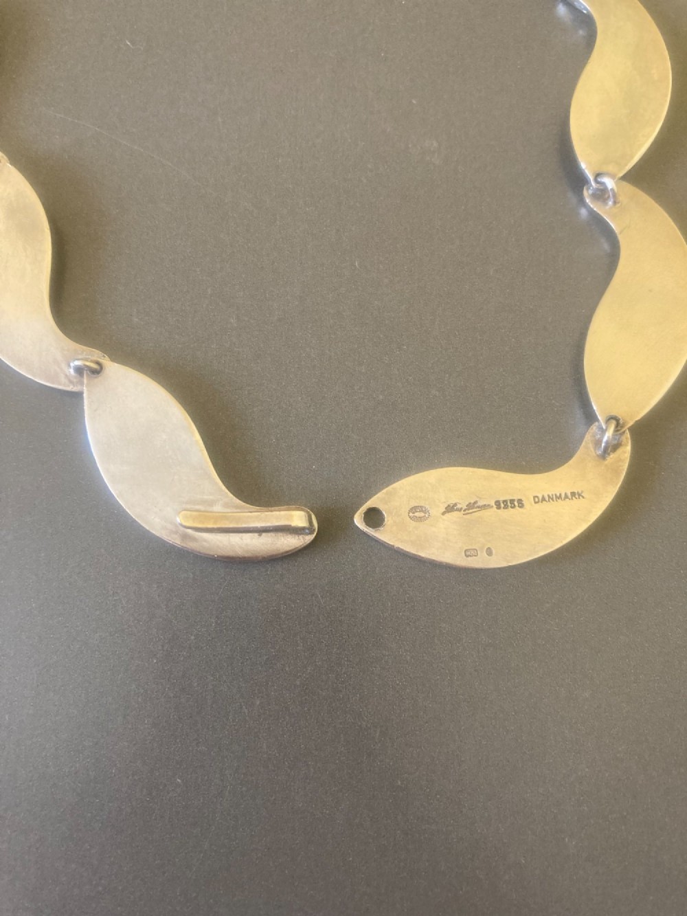 A Georg Jensen 1960s Danish sterling silver necklace featuring contoured, wave-like articulated links arranged in a circular shape. View VI