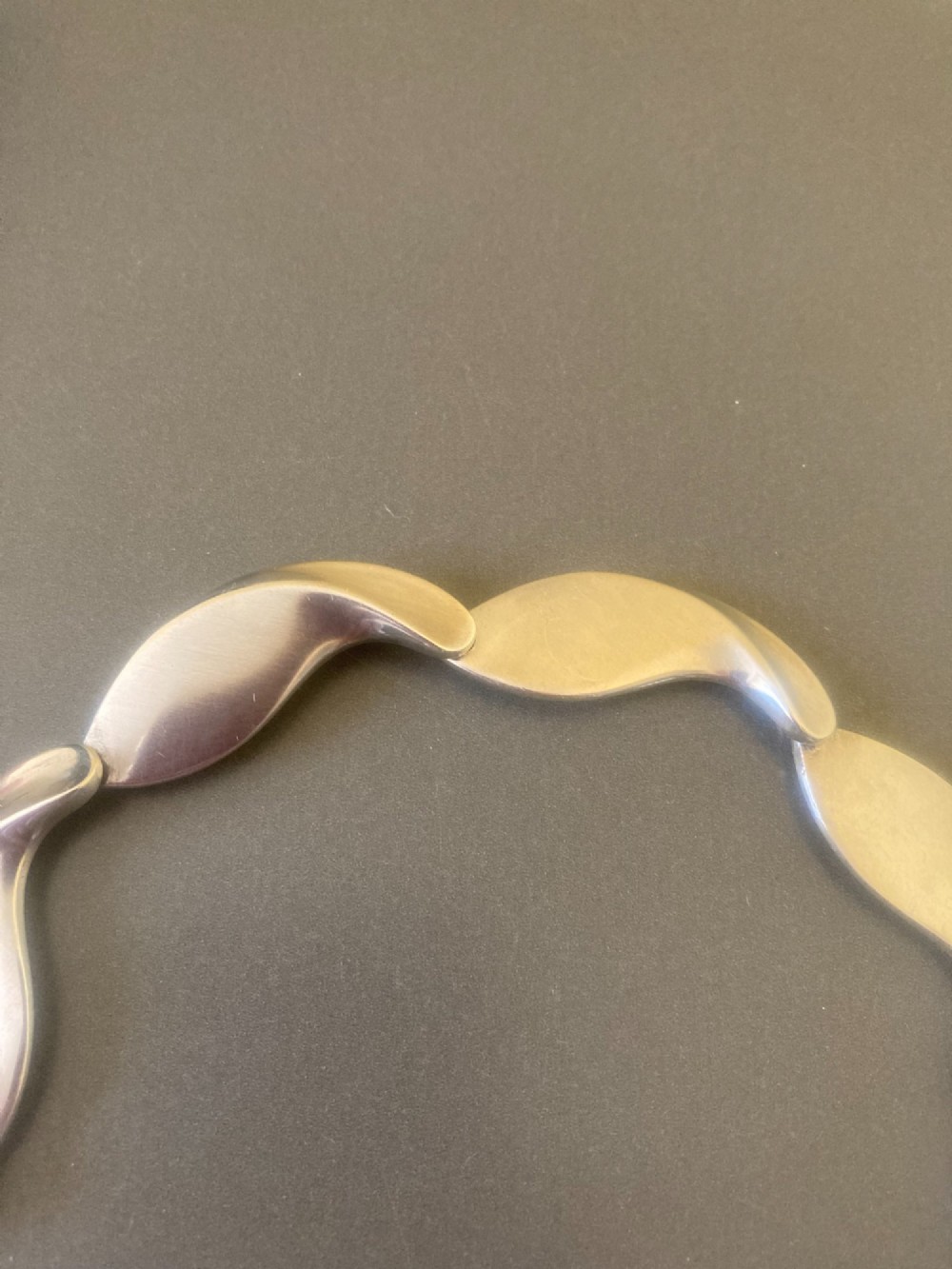 A Georg Jensen 1960s Danish sterling silver necklace featuring contoured, wave-like articulated links arranged in a circular shape. View VIII
