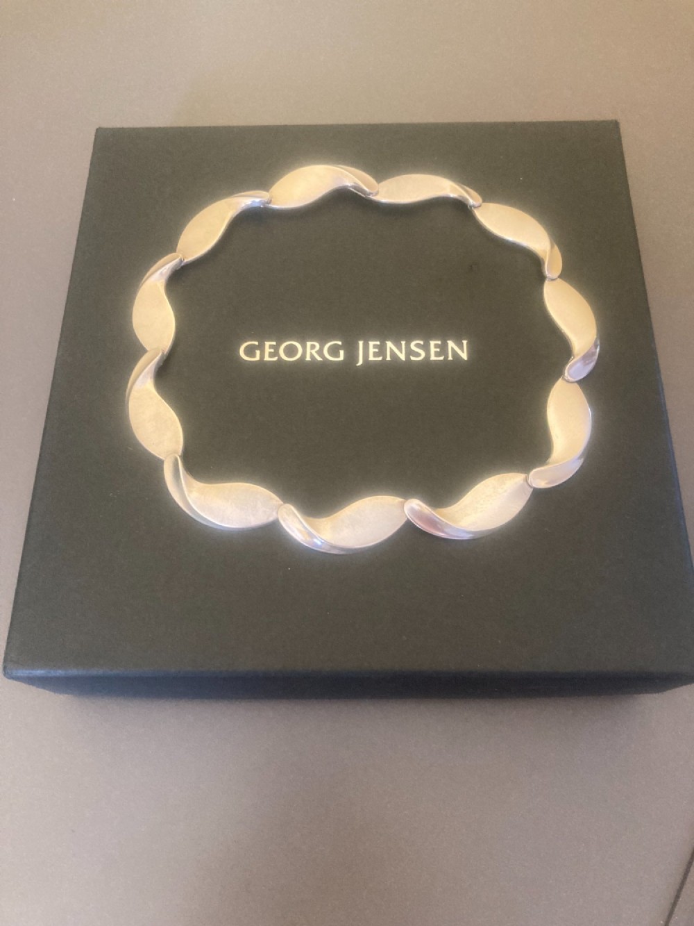 A Georg Jensen 1960s Danish sterling silver necklace featuring contoured, wave-like articulated links arranged in a circular shape. View IX