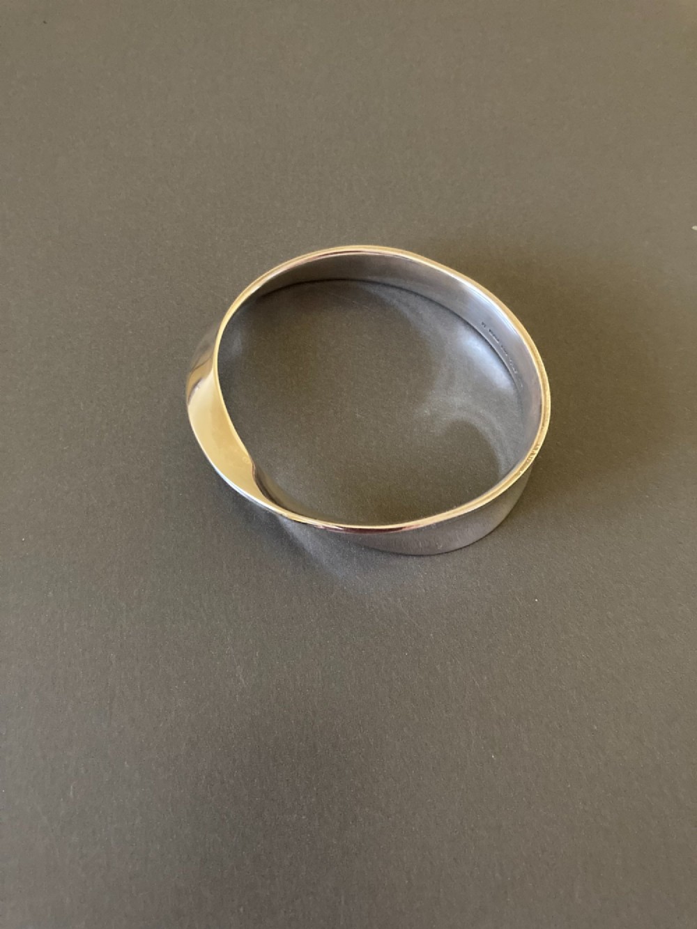 A polished sterling silver Mobius bangle featuring a continuous twisted geometric loop.