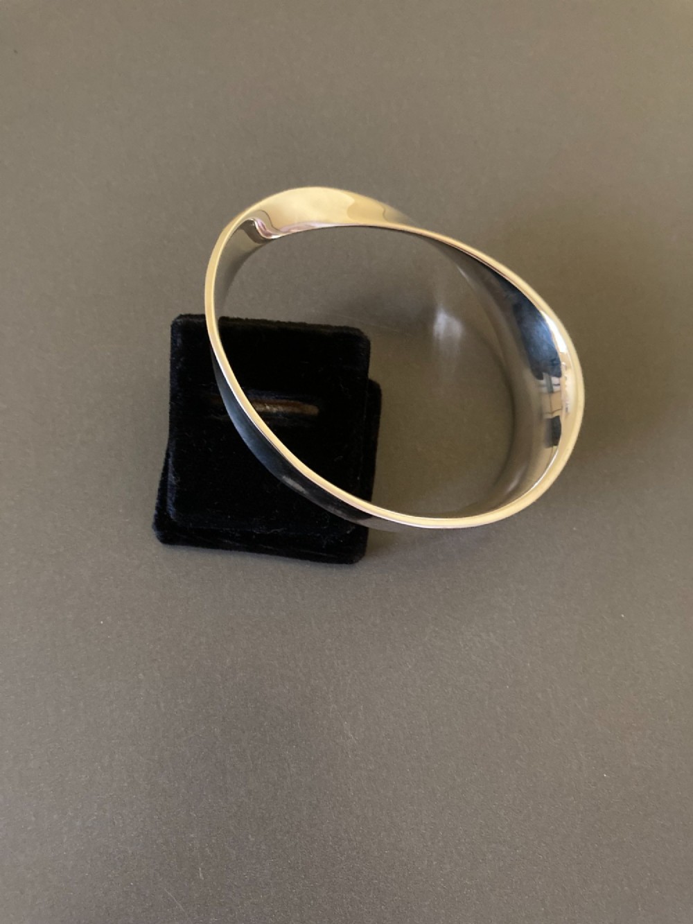 A polished sterling silver Mobius bangle featuring a continuous twisted geometric loop. View II