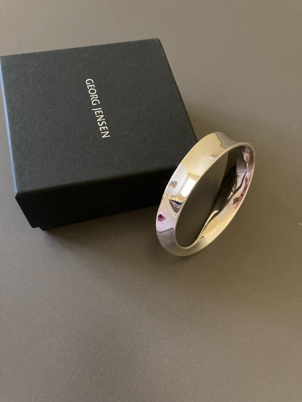 A polished sterling silver Mobius bangle featuring a continuous twisted geometric loop. View IV