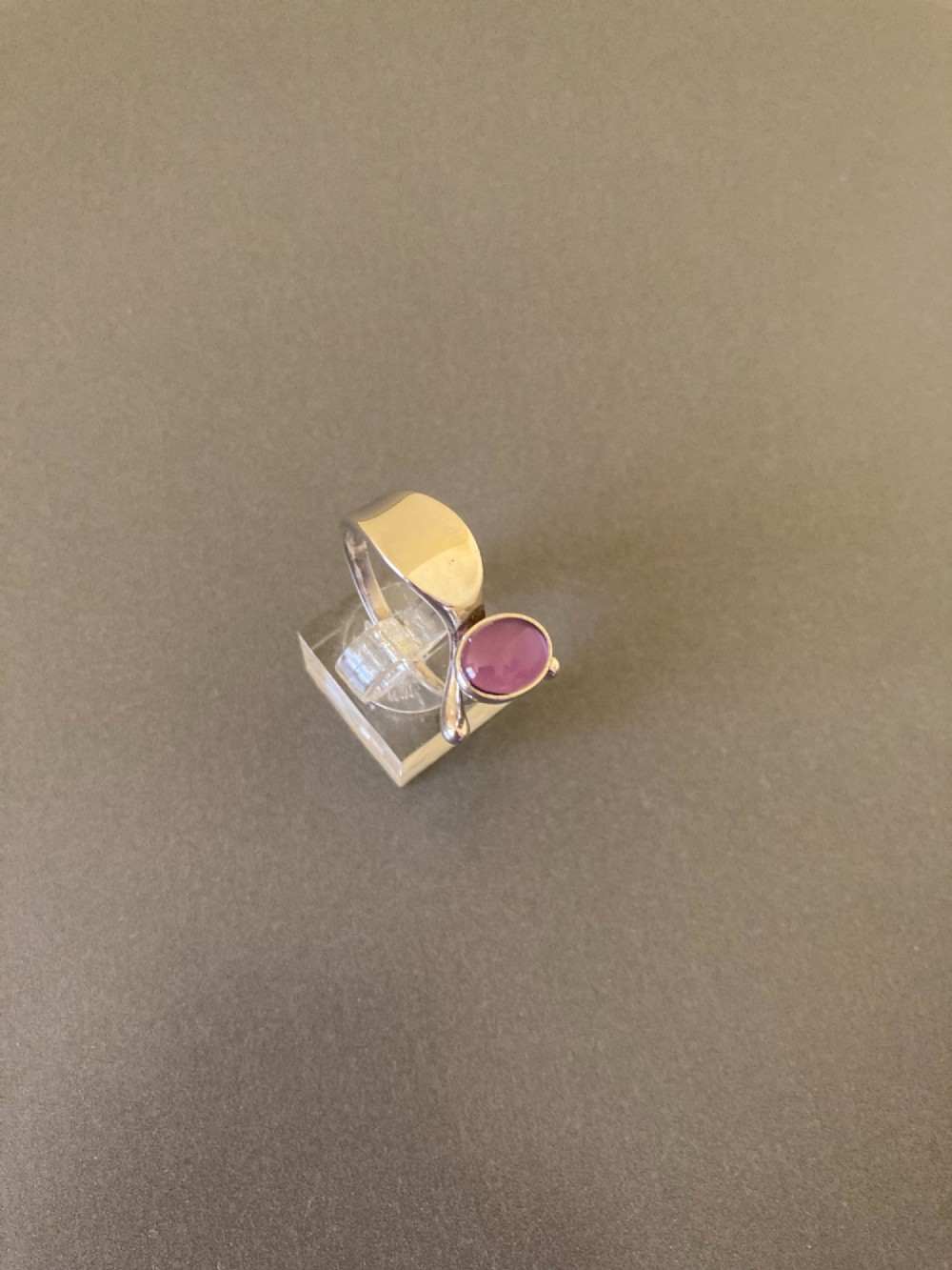A sterling silver ring featuring a fluid organic band set with an offset oval purple cabochon amethyst. View II