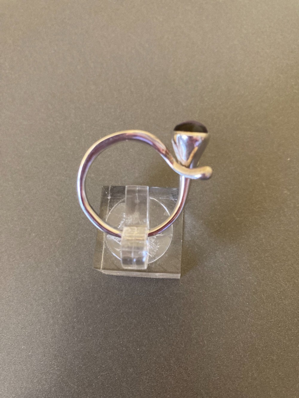 A sterling silver ring featuring a fluid organic band set with an offset oval purple cabochon amethyst. View III