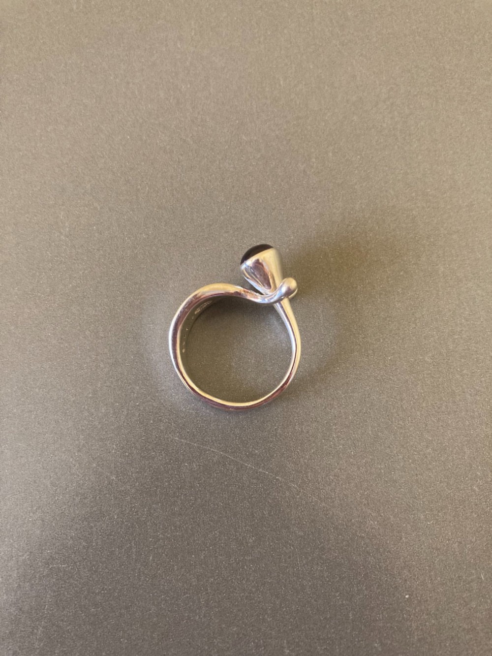 A sterling silver ring featuring a fluid organic band set with an offset oval purple cabochon amethyst. View IV