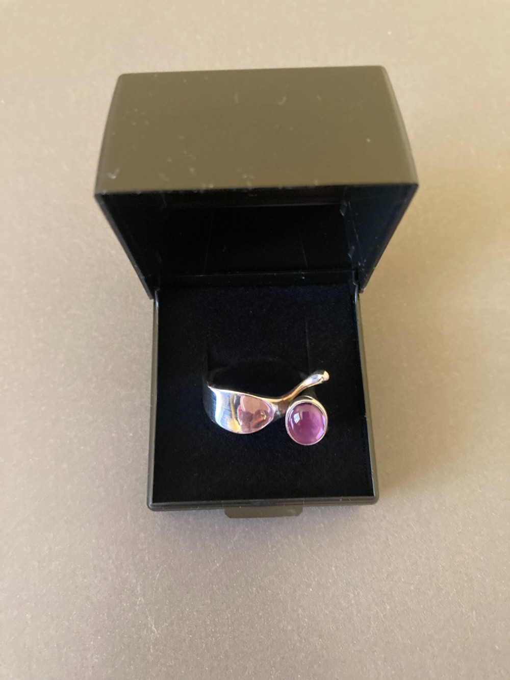 A sterling silver ring featuring a fluid organic band set with an offset oval purple cabochon amethyst. View VI
