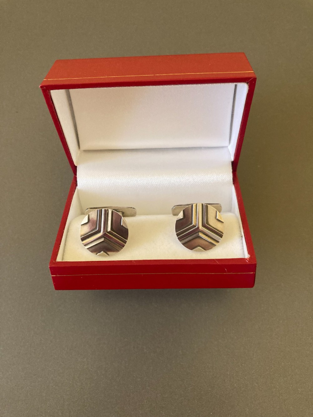 A pair of round sterling silver cufflinks featuring a stylized geometric chevron design with oxidised accents.