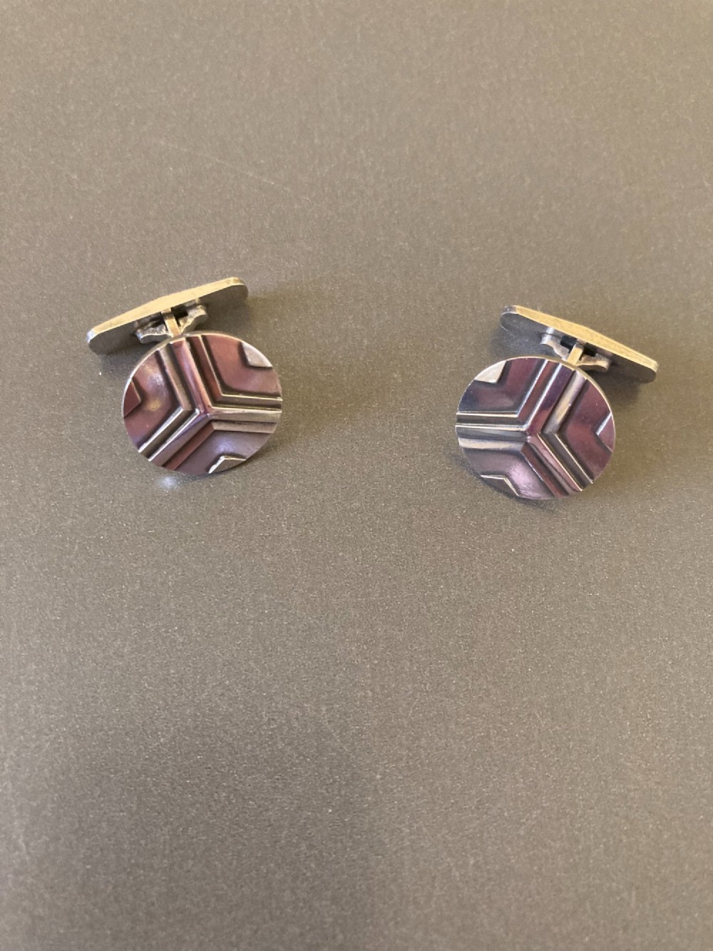 A pair of round sterling silver cufflinks featuring a stylized geometric chevron design with oxidised accents. View III