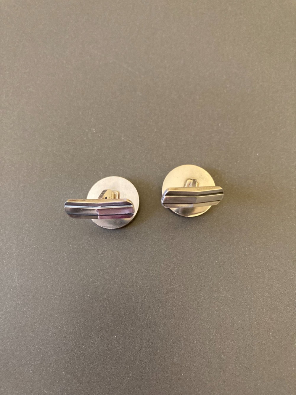 A pair of round sterling silver cufflinks featuring a stylized geometric chevron design with oxidised accents. View V
