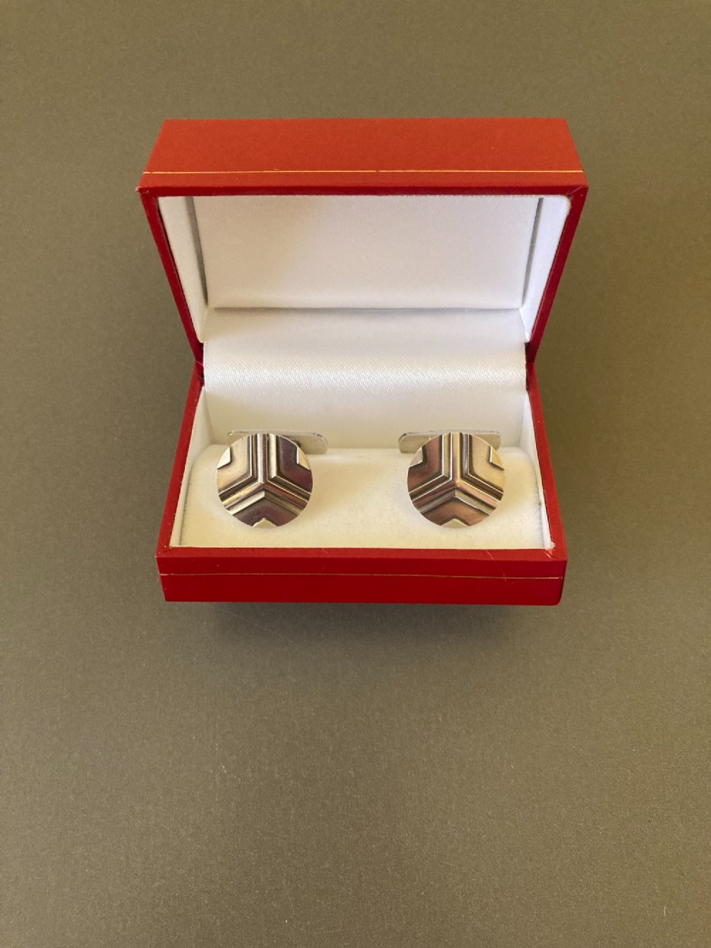 A pair of round sterling silver cufflinks featuring a stylized geometric chevron design with oxidised accents. View VII