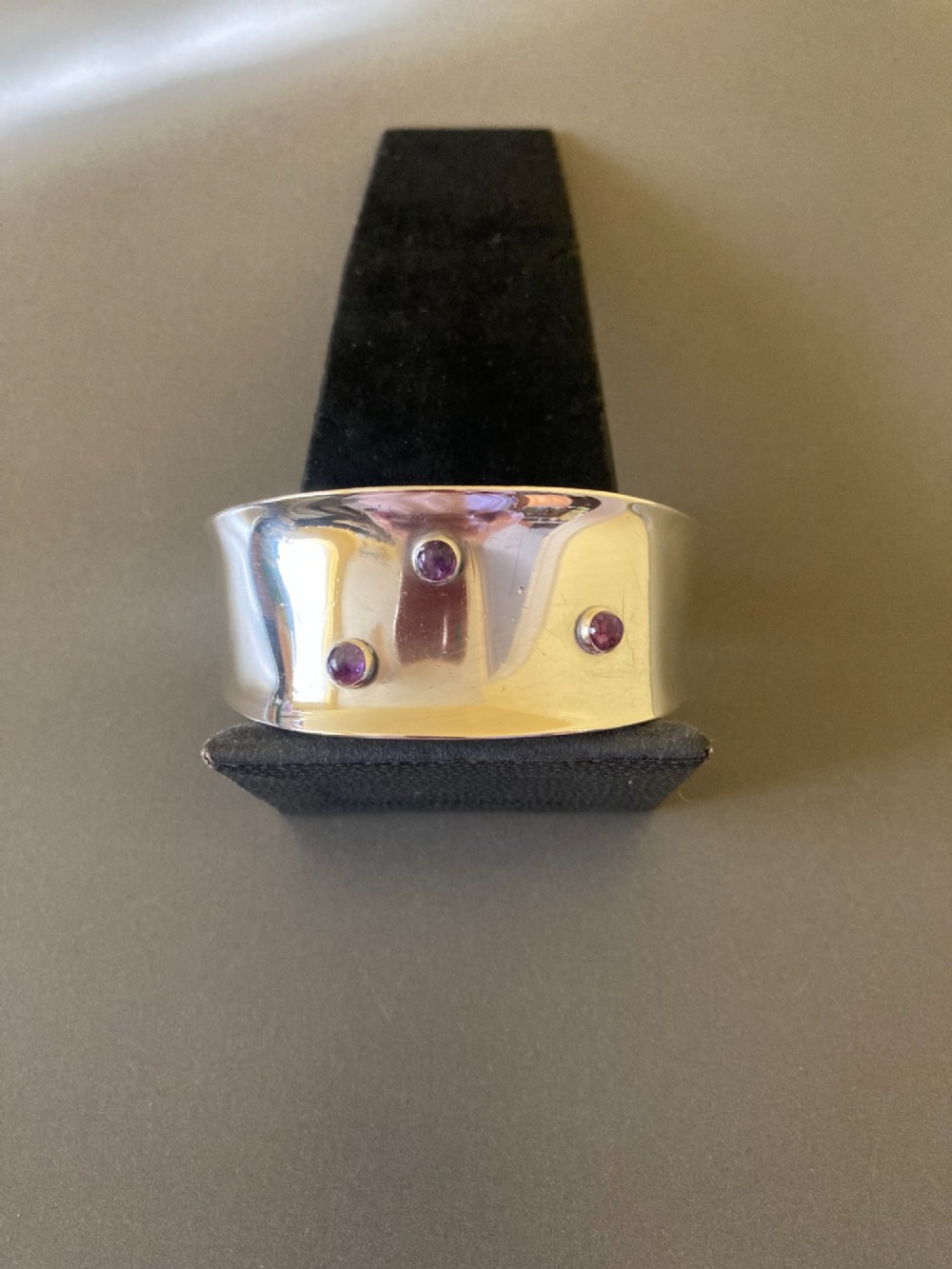 A wide sterling silver open cuff bracelet set with three round purple cabochon amethyst gemstones. View II