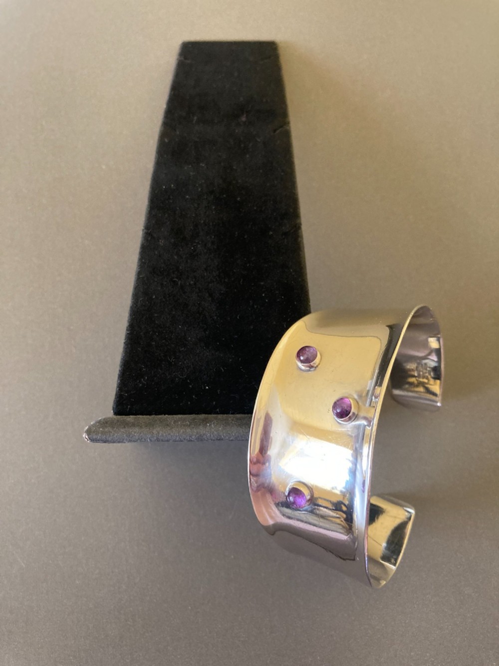 A wide sterling silver open cuff bracelet set with three round purple cabochon amethyst gemstones. View III