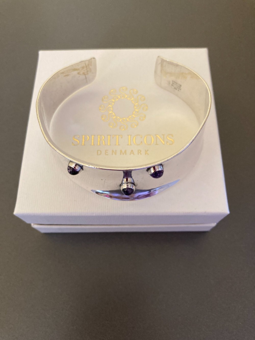 A wide sterling silver open cuff bracelet set with three round purple cabochon amethyst gemstones. View V
