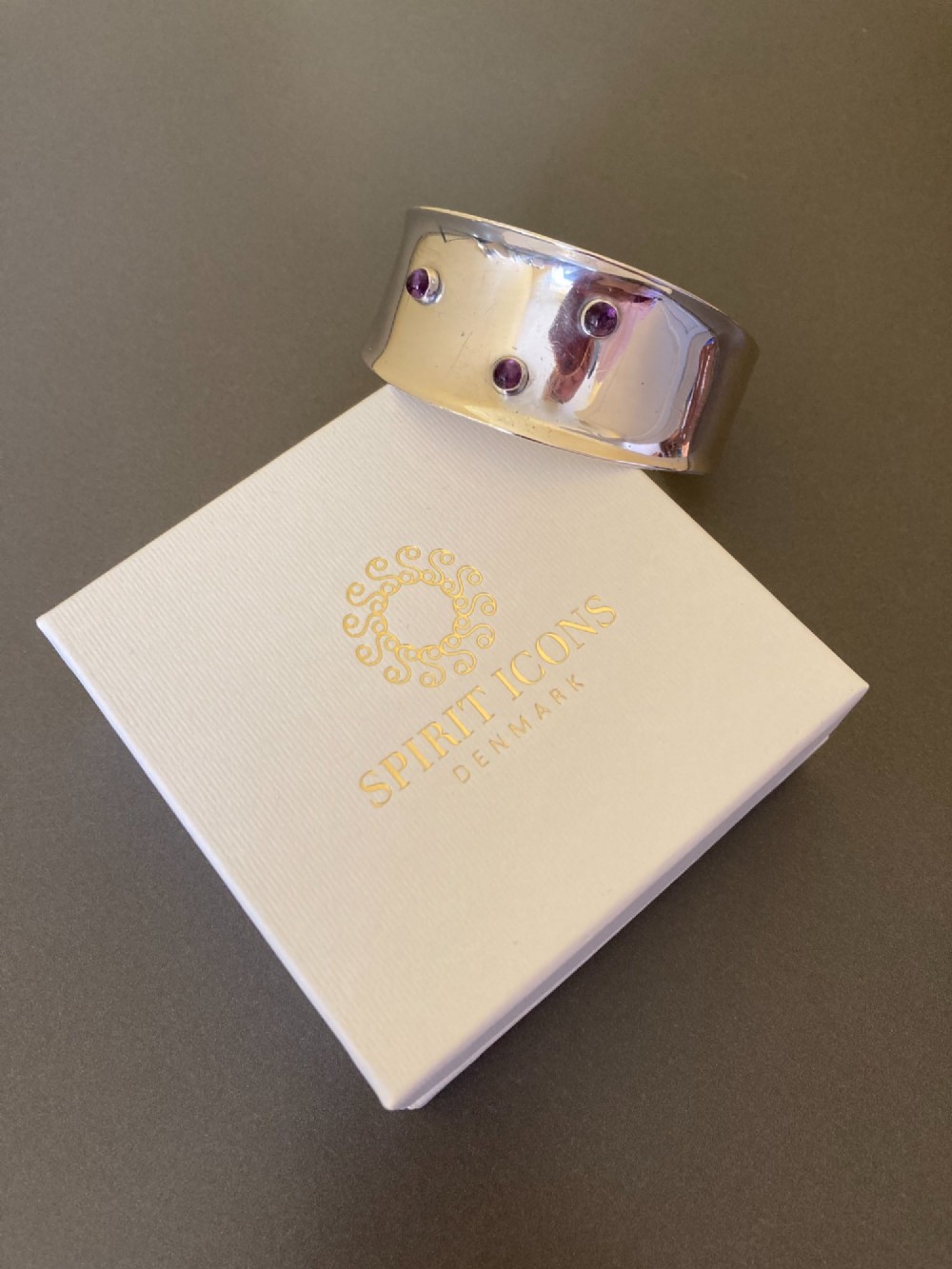 A wide sterling silver open cuff bracelet set with three round purple cabochon amethyst gemstones. View VI
