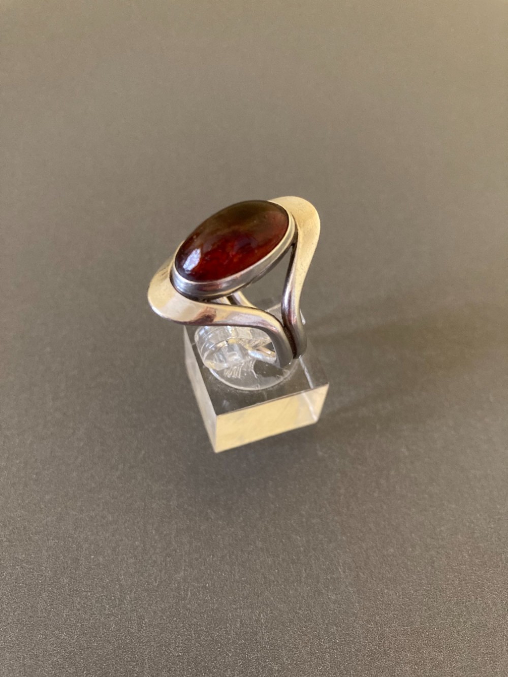 A mid-century Danish sterling silver ring featuring a central oval cabochon amber stone enclosed within a sculptural split-band frame. View II