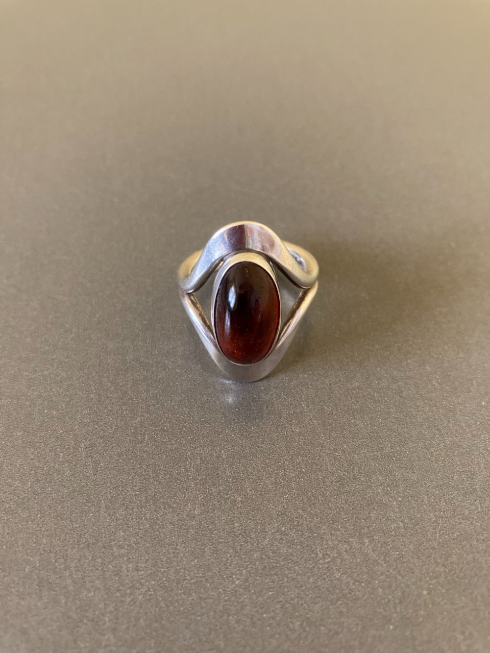 A mid-century Danish sterling silver ring featuring a central oval cabochon amber stone enclosed within a sculptural split-band frame. View III