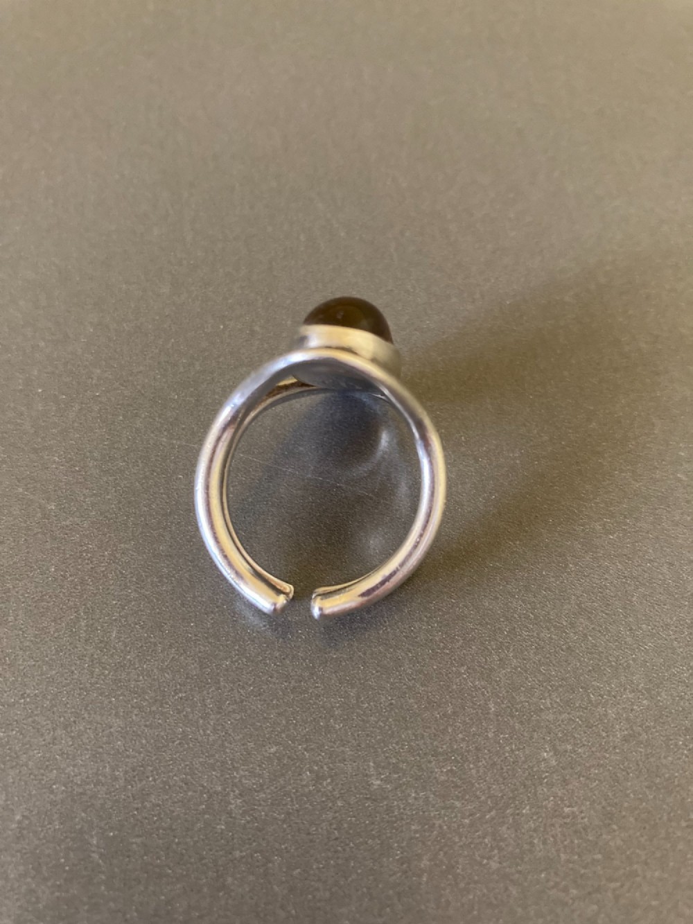 A mid-century Danish sterling silver ring featuring a central oval cabochon amber stone enclosed within a sculptural split-band frame. View V